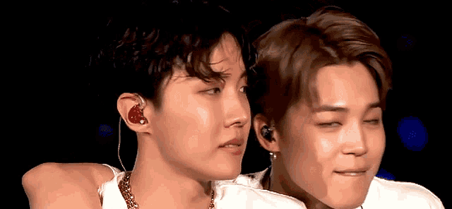 a close up of two men 's faces with one wearing earbuds