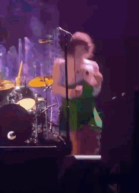 a person standing on a stage with a microphone and a drum set