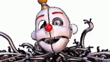 a clown with a red nose is surrounded by a bunch of wires and is looking at the camera .