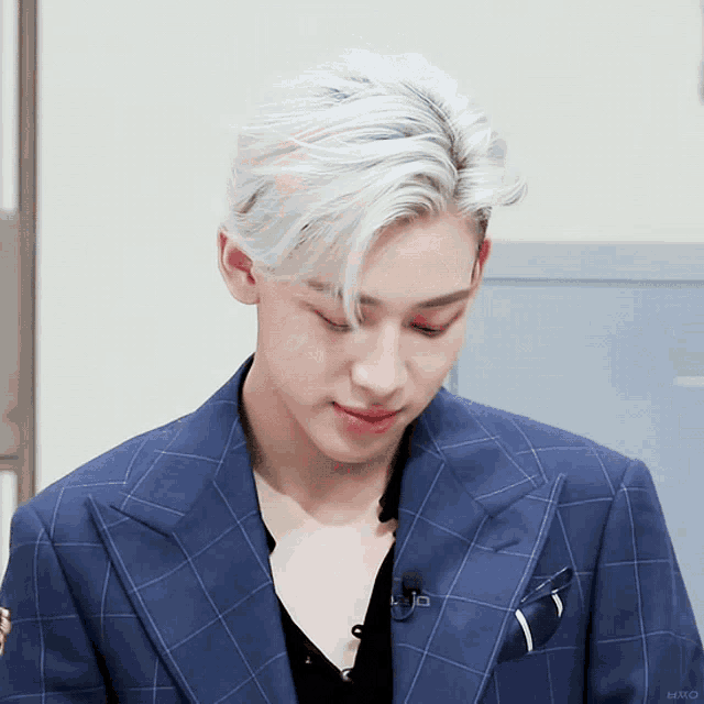 a man with white hair is wearing a blue plaid jacket and a black shirt