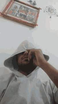 a person covering their face with a white cloth in front of a framed picture of a family