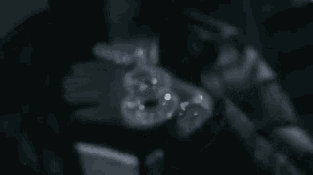 a black and white photo of a person holding a donut in their hand