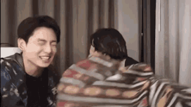 a couple of men are laughing together in a room .