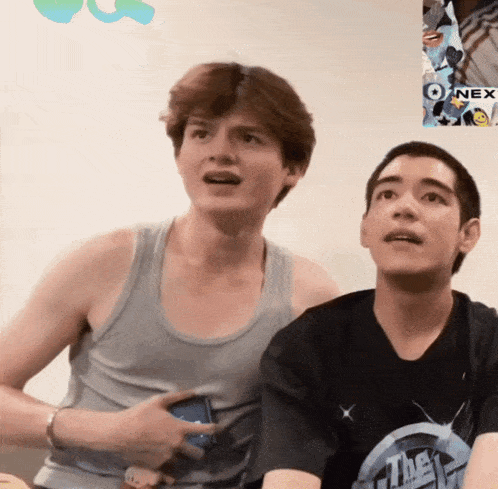 two young men are playing a video game and one of them is wearing a shirt that says ' the ' on it