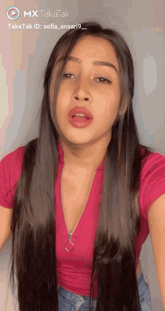 a woman with long hair is wearing a pink top