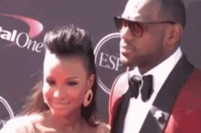 a man and a woman are standing on a red carpet .