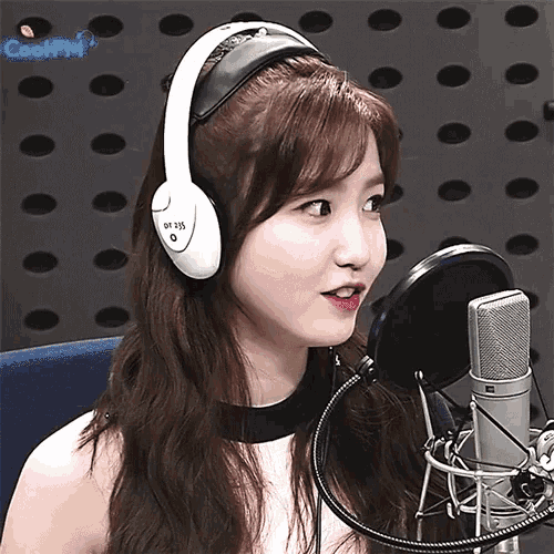 a girl wearing headphones stands in front of a microphone with the words cool fm on the bottom left