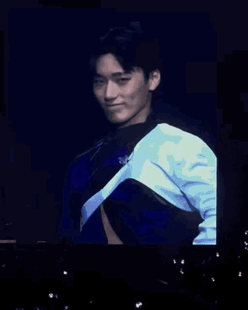 a man in a crop top is dancing on a stage in front of a screen .