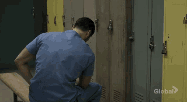 a man sits on a bench in a locker room while a woman stands behind him and says good day