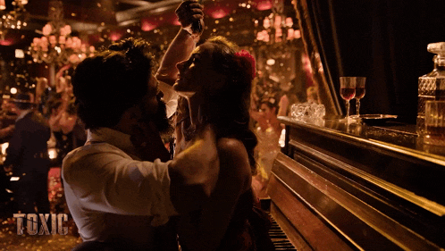 a man and woman are dancing in front of a piano with the word toxic on the bottom