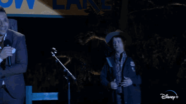 two men singing on stage in front of a sign that says camp allen lake