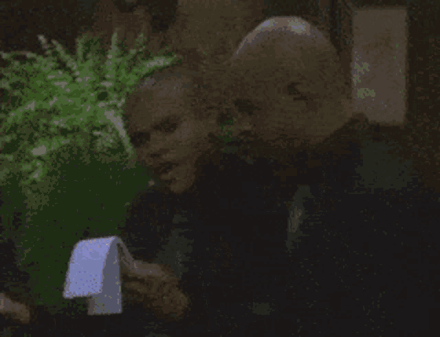 a bald man is holding a piece of paper in his hand