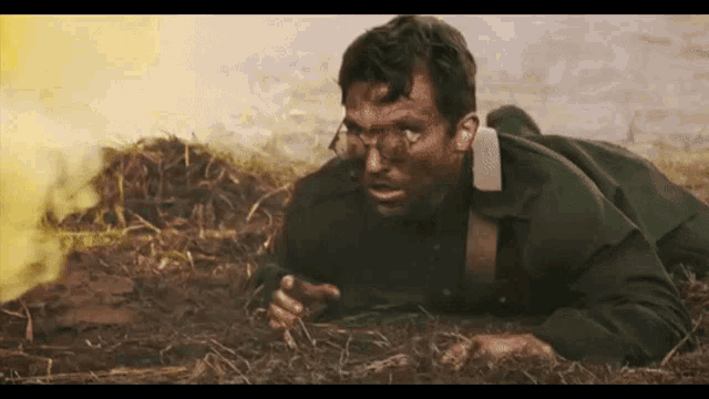 a man in a military uniform is laying on the ground in front of a fire