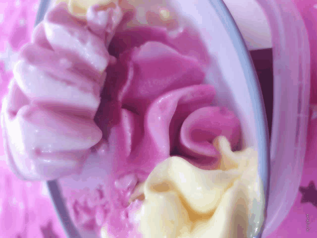 a bowl of pink and yellow ice cream on a pink table
