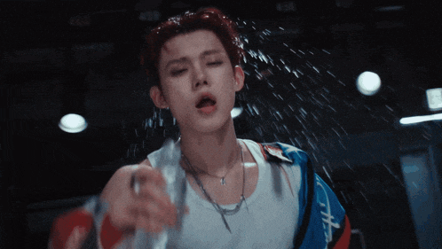 a man in a white tank top is spraying water on his face