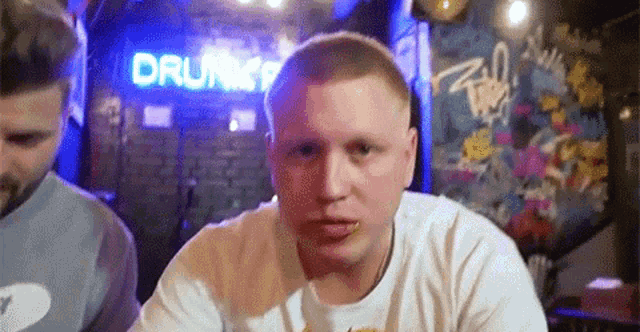 a man is sitting in front of a sign that says drunk