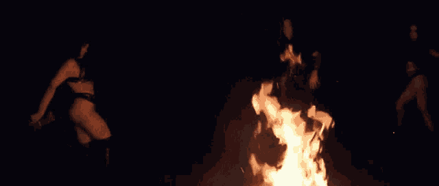 a group of women dancing in front of a fire