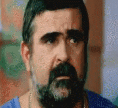 a man with a beard is wearing a blue shirt and a necklace