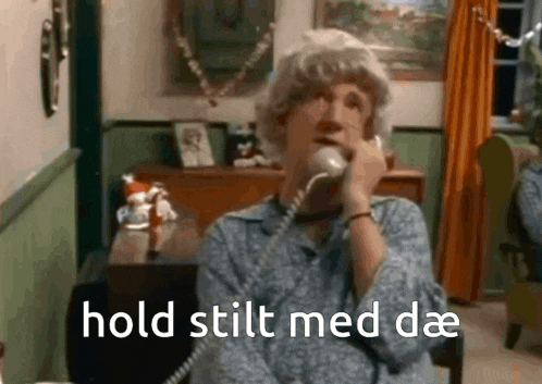 a man in a wig is talking on a phone with the words hold stilt med dae written below him