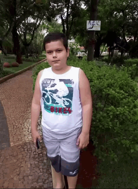a young boy wearing a white tank top that says bikes on it