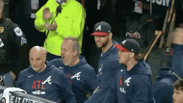 a group of men standing next to each other in a dugout .