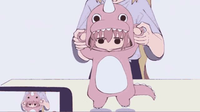 a girl is wearing a pink dinosaur costume with a horn on her head