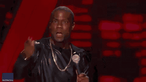 a man in a black jacket is holding a microphone and making a face .
