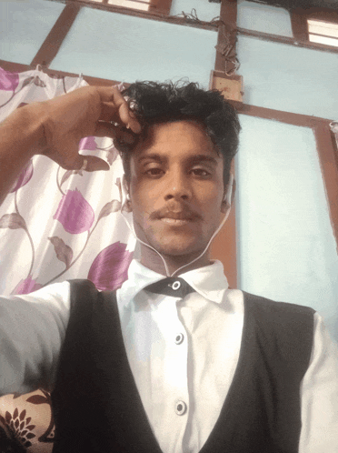 a man wearing ear buds takes a selfie in front of a purple and white curtain