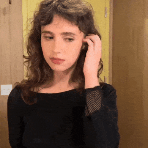 a woman in a black shirt is adjusting her hair