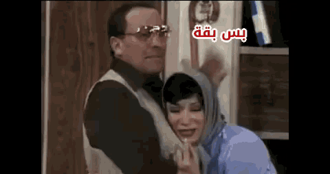 a man and a woman are standing next to each other with arabic writing on the bottom right