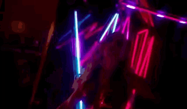 a person is standing in front of a bunch of neon lights with the words `` indecente '' written on the bottom .
