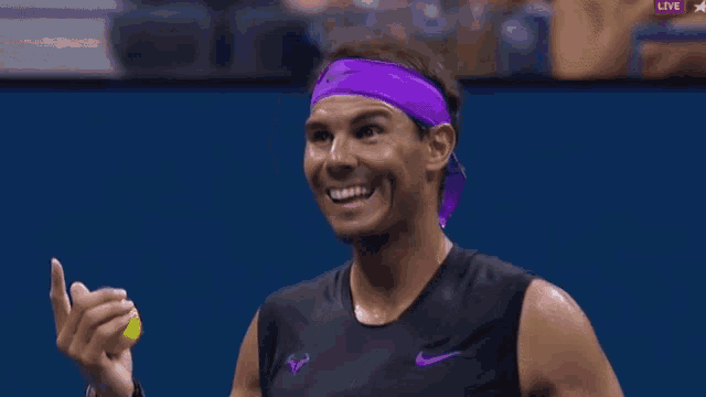 a man wearing a purple headband holds a tennis ball in his hand