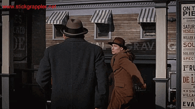 two men are walking in front of a building that has the word grav on it
