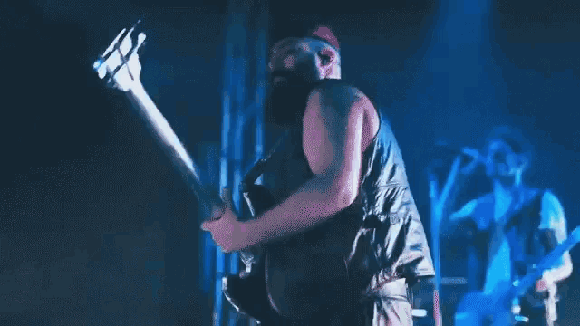 a man with a beard is playing a bass guitar on stage