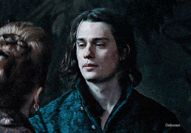 a man with long hair is looking at a woman with her eyes closed in a dark room .