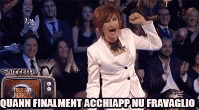 a woman in a white suit stands in front of a crowd with the words " quann finalment acchiapp nu fravaglio "