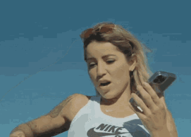a woman with a tattoo on her arm is holding a cell phone and says that 's what i like to hear awesome