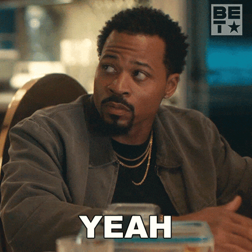 a man with a beard is sitting at a table and the word yeah is on the screen