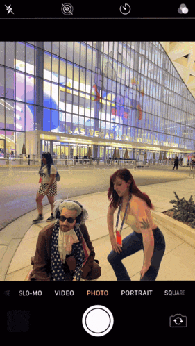 a phone screen shows a woman taking a picture of a man in front of a building that says las vegas