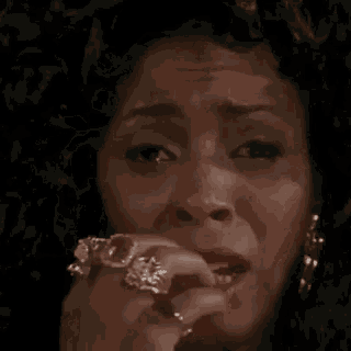 a close up of a woman 's face with a hand on her forehead .