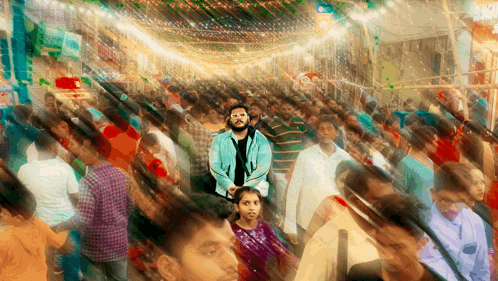 a man in a blue jacket stands in the middle of a crowd of people