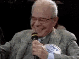 an older man is holding a microphone and smiling .