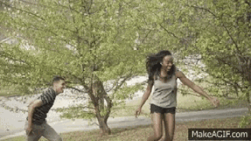 a man and a woman are running across a path in a park .