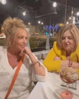 two women are sitting at a table drinking wine .