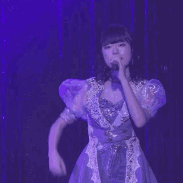 a woman in a purple dress is flexing her arm