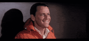a man wearing a red jacket is smiling
