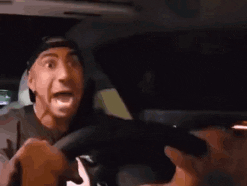 a man is sitting in the driver 's seat of a car holding a gun .