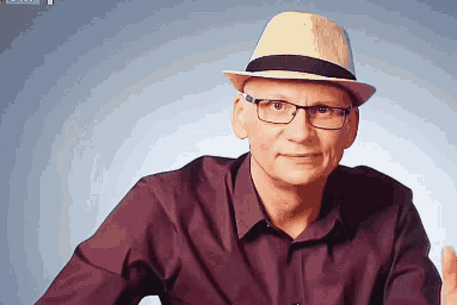 a man wearing glasses and a hat is smiling