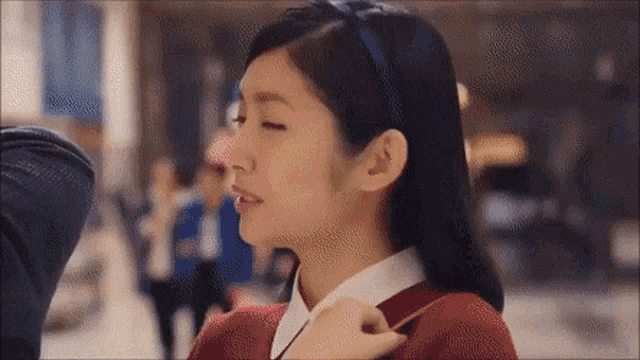 a woman wearing a headband and a red sweater is looking down