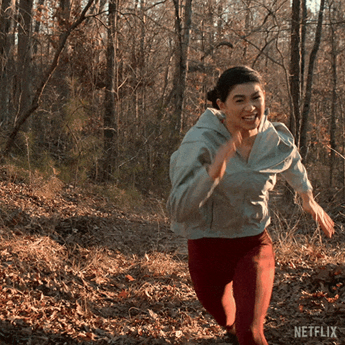 a woman is running in the woods with a netflix logo in the background